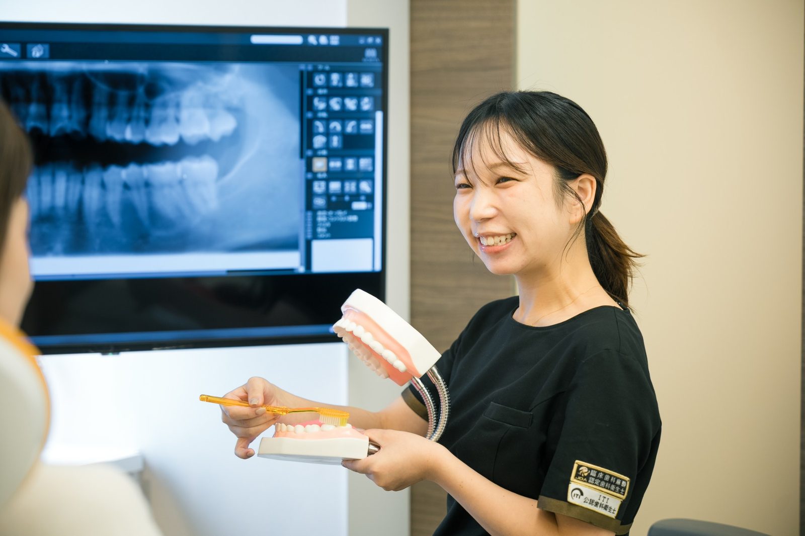 認定資格のワッペンを着けた歯科衛生士がブラッシングを指導している様子