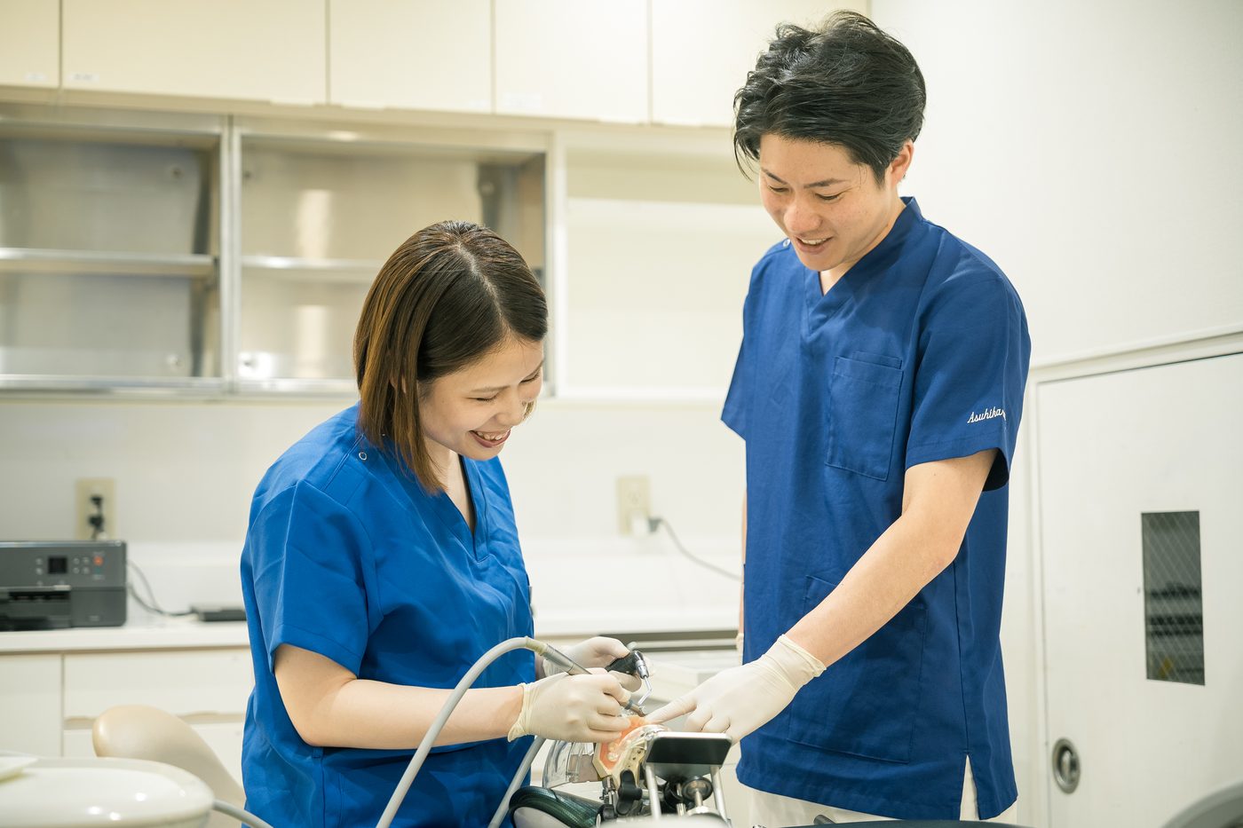 先輩の歯科医師が後輩に器具の扱いを教えている様子